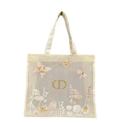 A sheer off-white mesh tote bag with a gold-tone CD logo in the center, decorated with embroidered butterflies, dragonflies, and floral motifs in soft pink, beige, and white. The bag features two wide shoulder straps and is photographed against a solid white background.