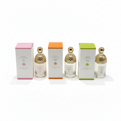 Four perfume bottles with textured gold caps are arranged in front of their colored boxes (pink, orange, and green) and a white drawstring bag with gold trim on a white background. The brand name 'Alia Al-Safa' is visible on the packaging.