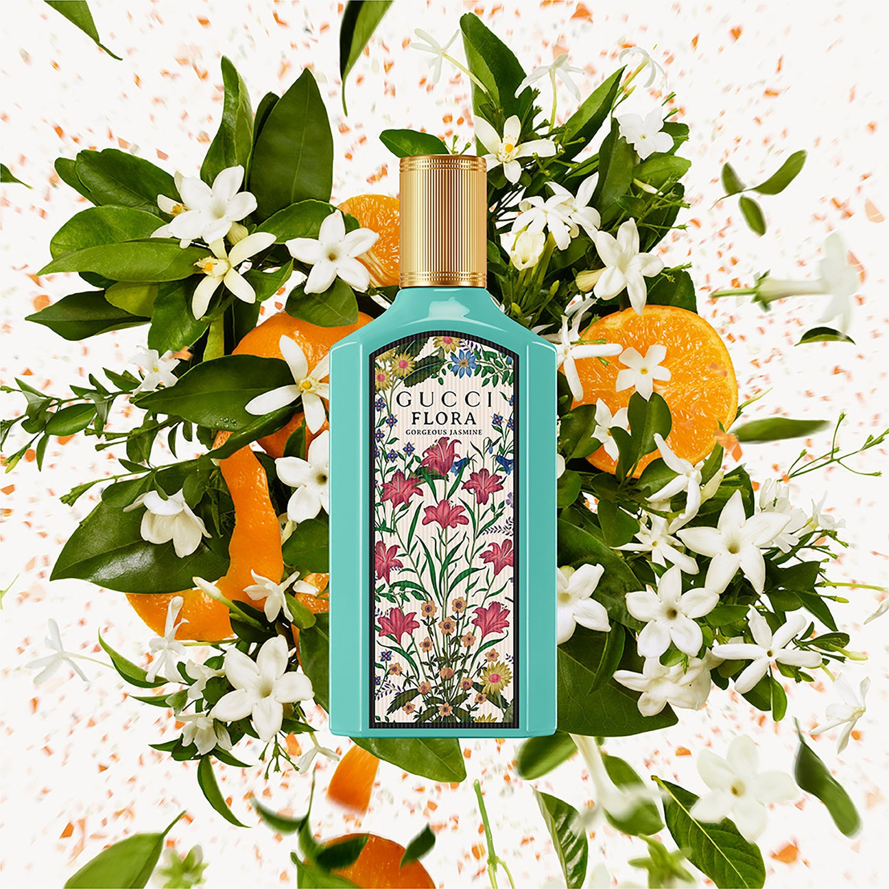 Gucci Flora perfume bottle surrounded by flowers and oranges on a decorative background