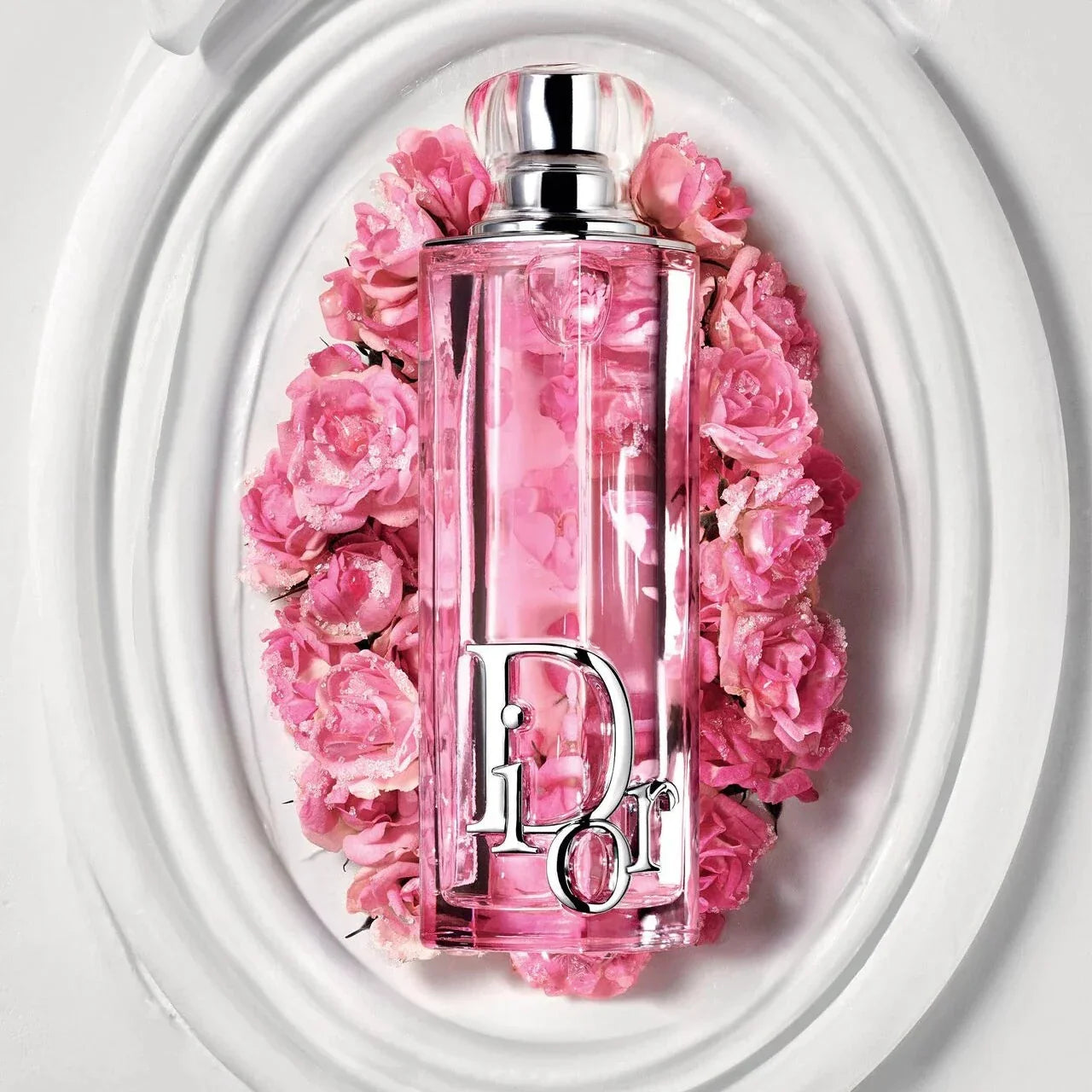 Pink perfume bottle with floral design and 'Dior' logo against a white background