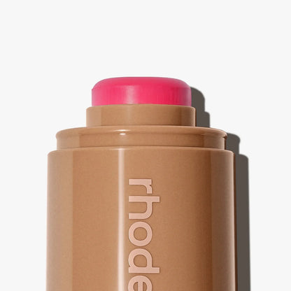 Cosmetic stick with pink cap on a white background, featuring the brand 'rhode'.