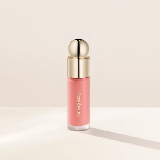 Pink lip gloss with gold cap on a beige background