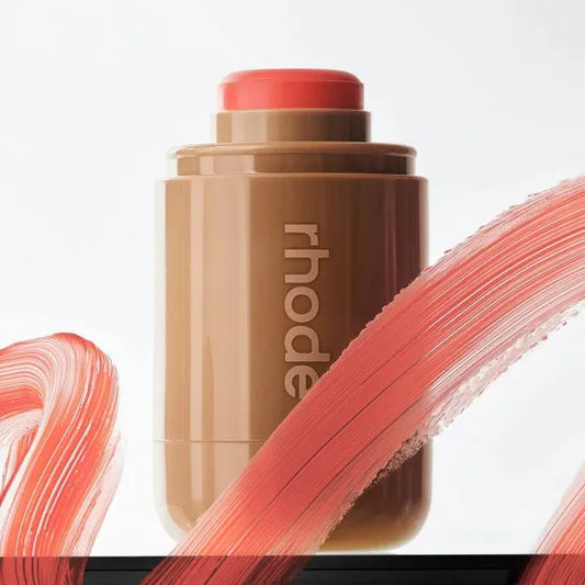 Makeup stick with 'rhode' branding and swatches on a light background
