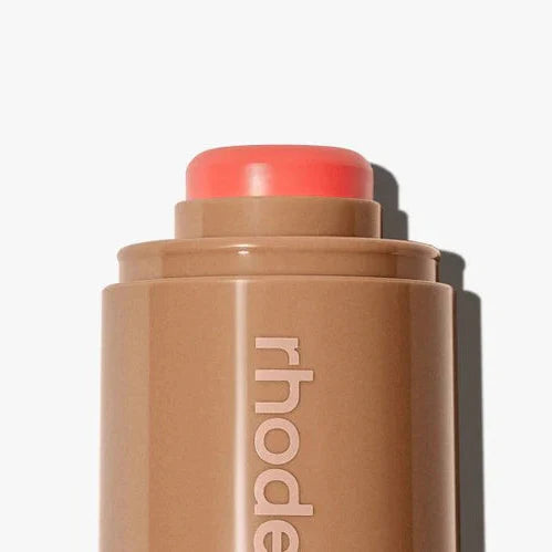 Makeup stick with coral-colored cap on a white background