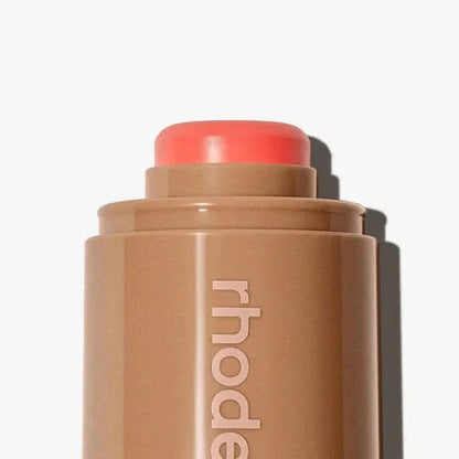Makeup stick with coral-colored cap on a white background