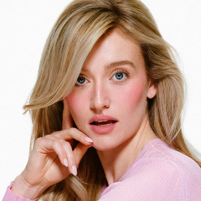 Woman with blonde hair wearing a pink sweater on a white background